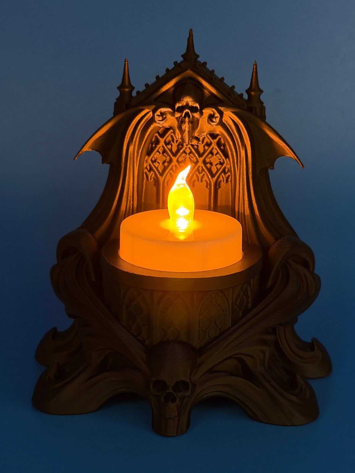 Matte black gothic skull and bat LED tealight holder with glowing flameless candle and ornate cathedral-style details.